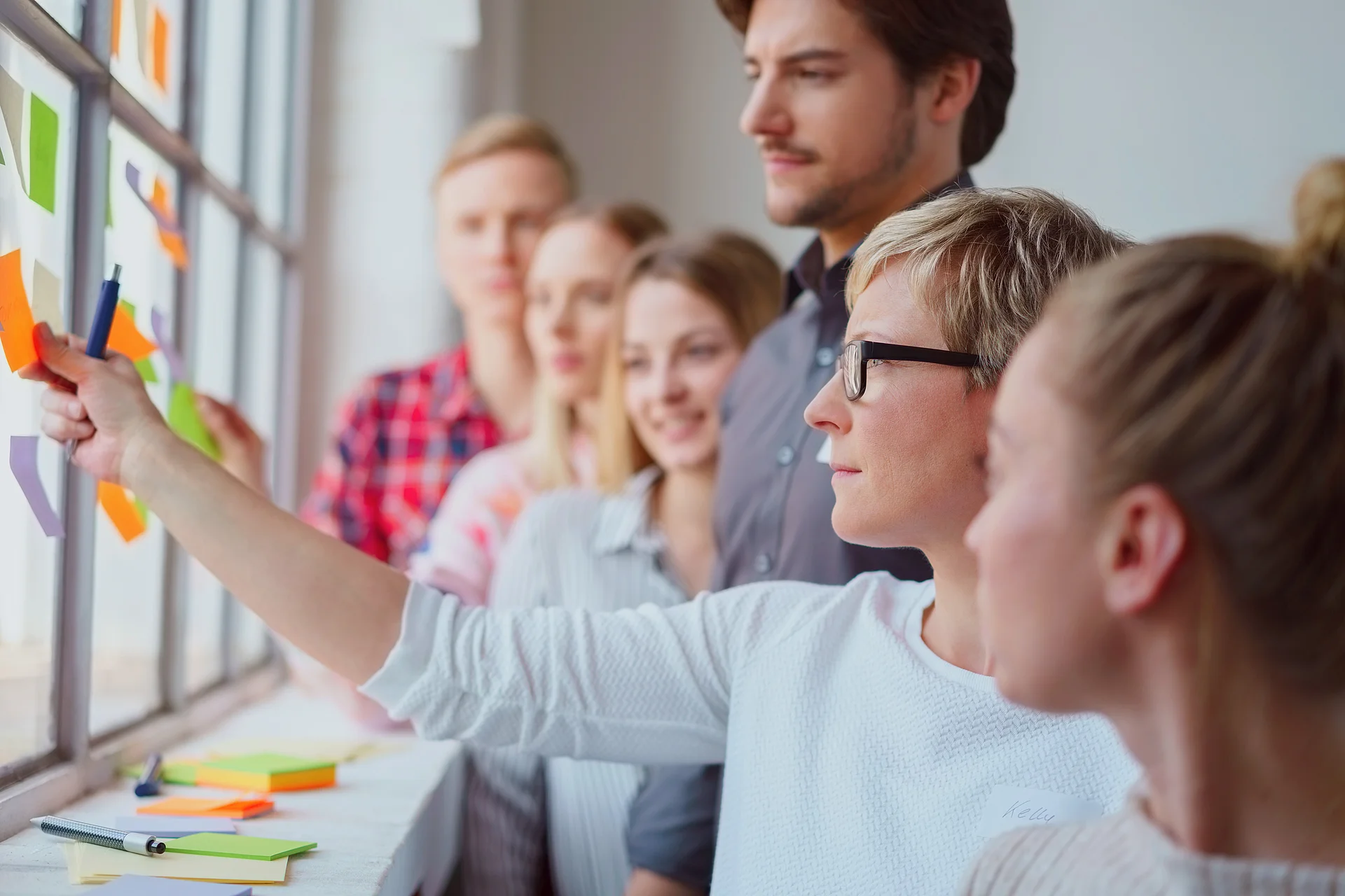 Qualifizierung durch kollaborative Weiterbildung und Teamarbeit Gruppe junger Erwachsener arbeitet gemeinsam an einer Glaswand mit Haftnotizen im Rahmen einer Weiterbildung