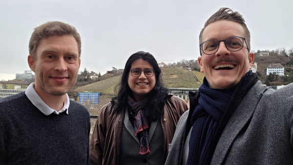 Selfie von zwei Männern und einer Frau. Sie lächeln in die Kamera im Hintergrund sind Weinberge und Häuser zu sehen.